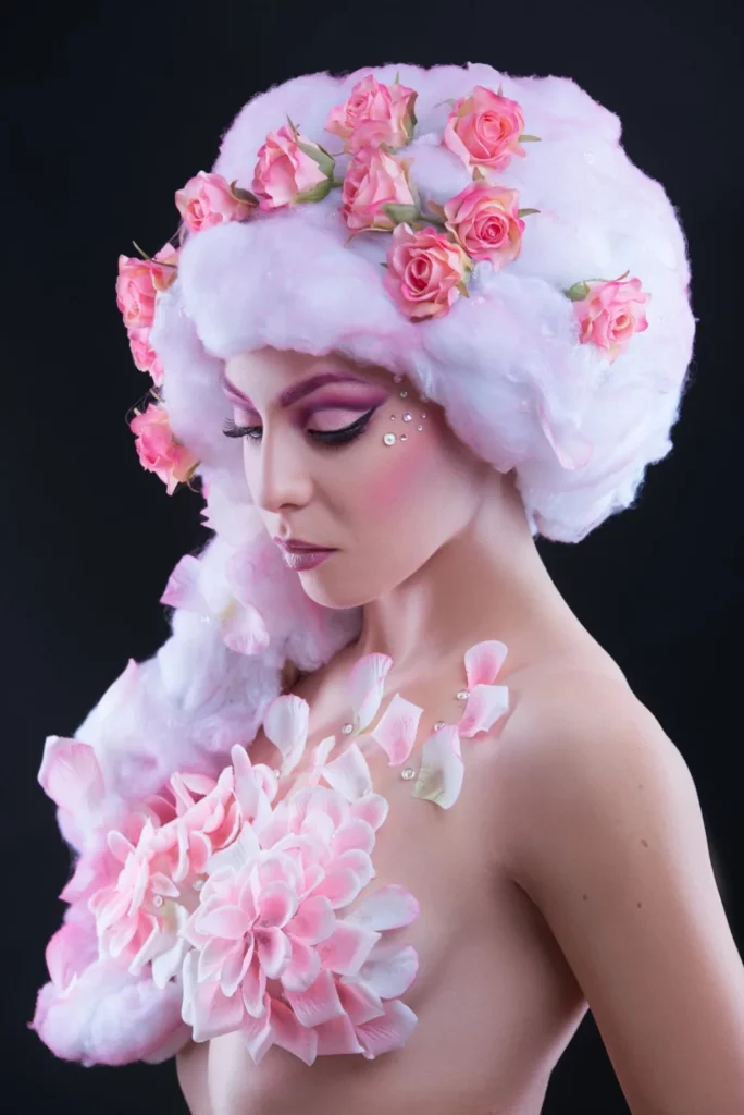 Portrait beauté avec coiffure florale rose et maquillage graphique.