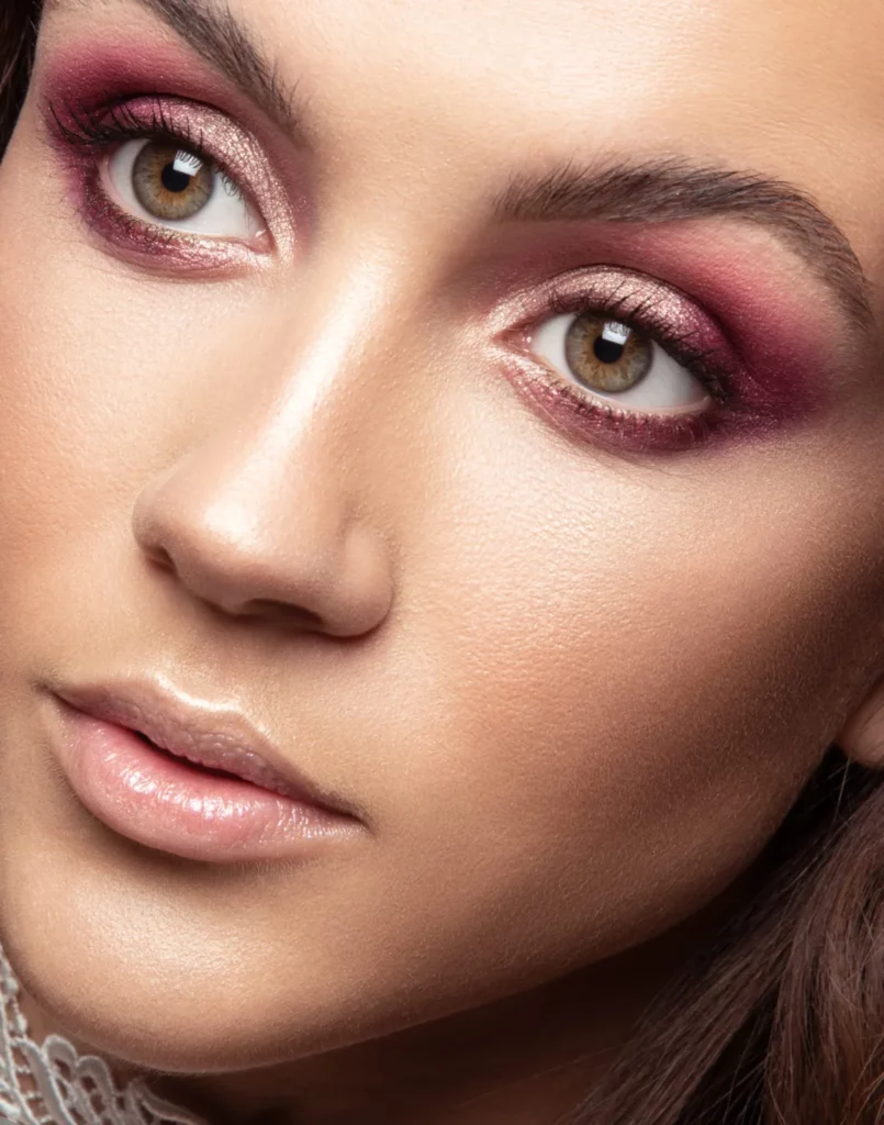 Gros plan beauté avec maquillage prune et regard dirigé vers l’objectif.