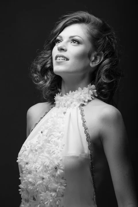 Portrait mode en noir et blanc d’une femme portant une tenue ornée de fleurs.