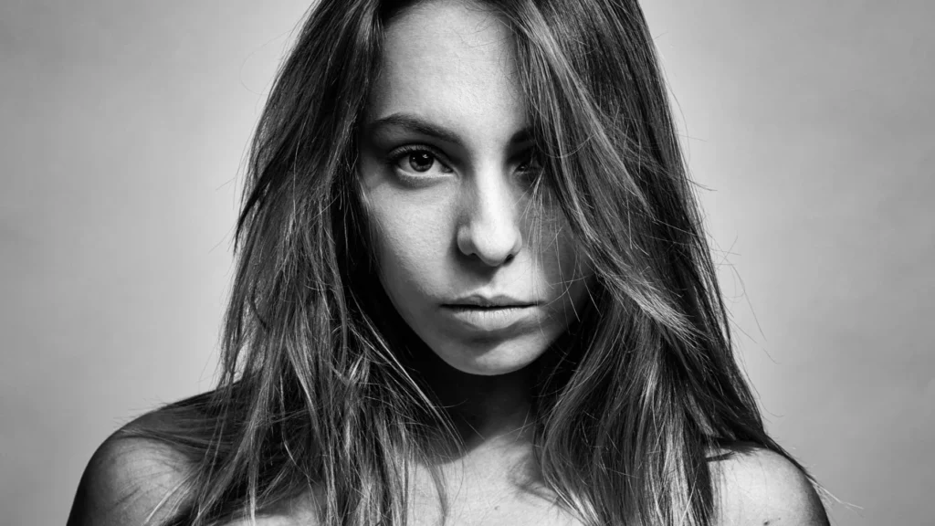 Portrait serré en noir et blanc d’une femme aux cheveux longs regardant l’objectif.