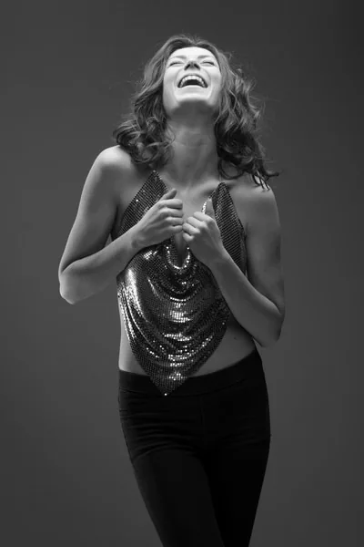 Portrait en noir et blanc d’une femme riant en studio.